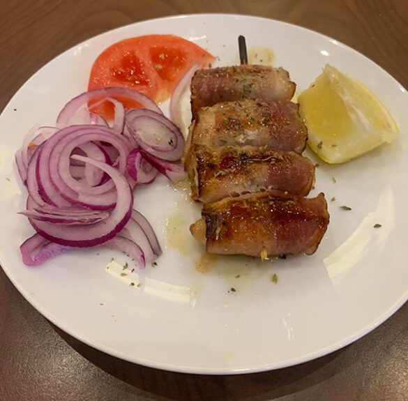 Une pièce de Souvlaki (brochette) de poulet au bacon.